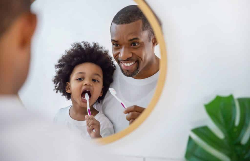 father and son brushing teeth pediatric dentist calgary