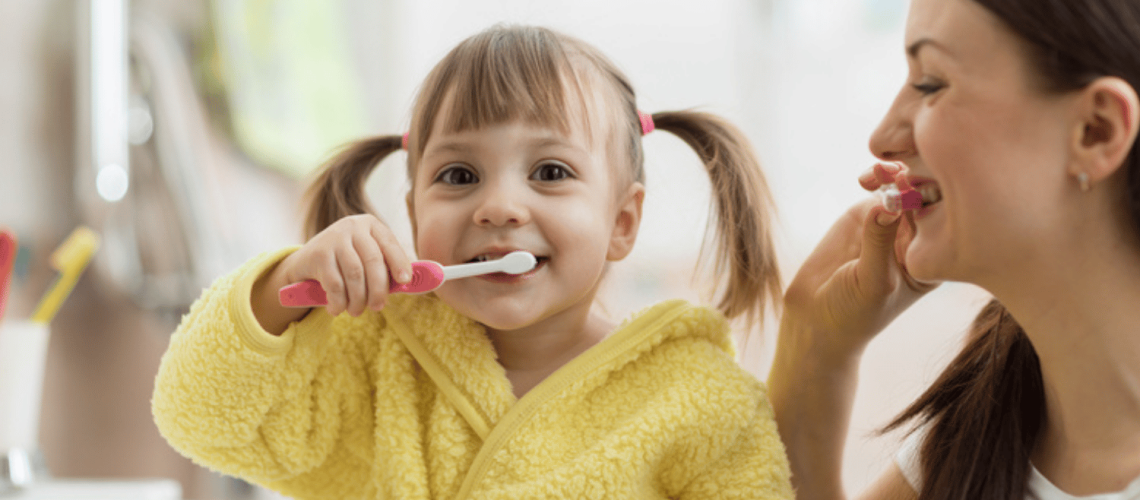 A child being taught how to brush her teeth