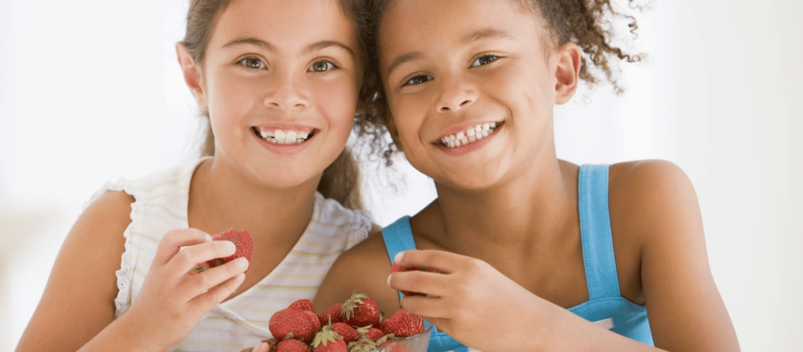Two kids eating strawberries